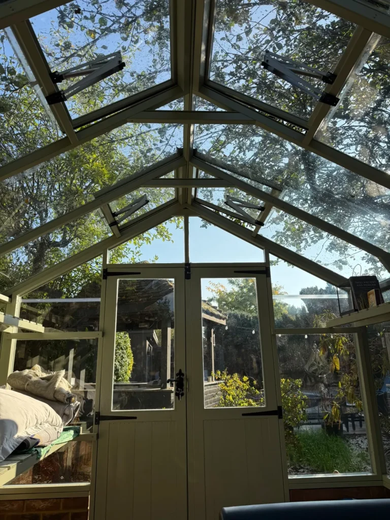 The pointed glass gable and painted double doors of the treatment room, with trees beyond